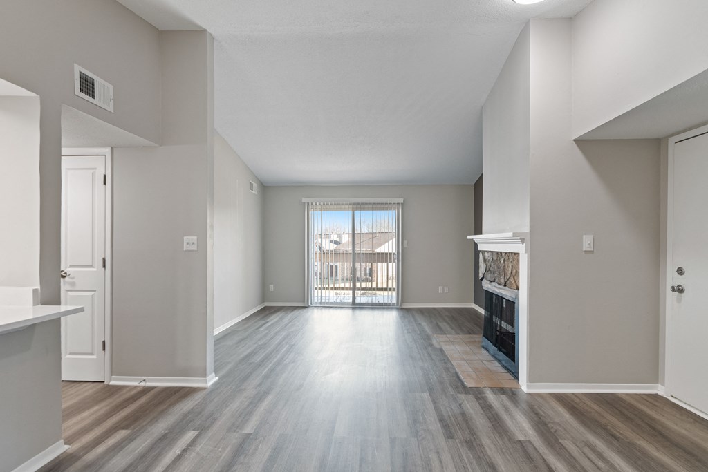 an empty living room with a fireplace and a door to a balcony