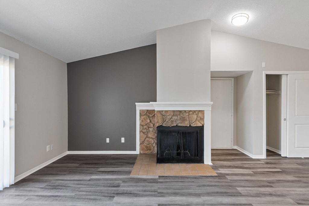 an empty living room with a fireplace and grey walls