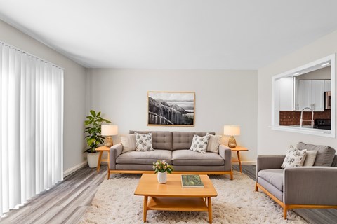 A living room with a grey couch, a coffee table, and a painting on the wall.