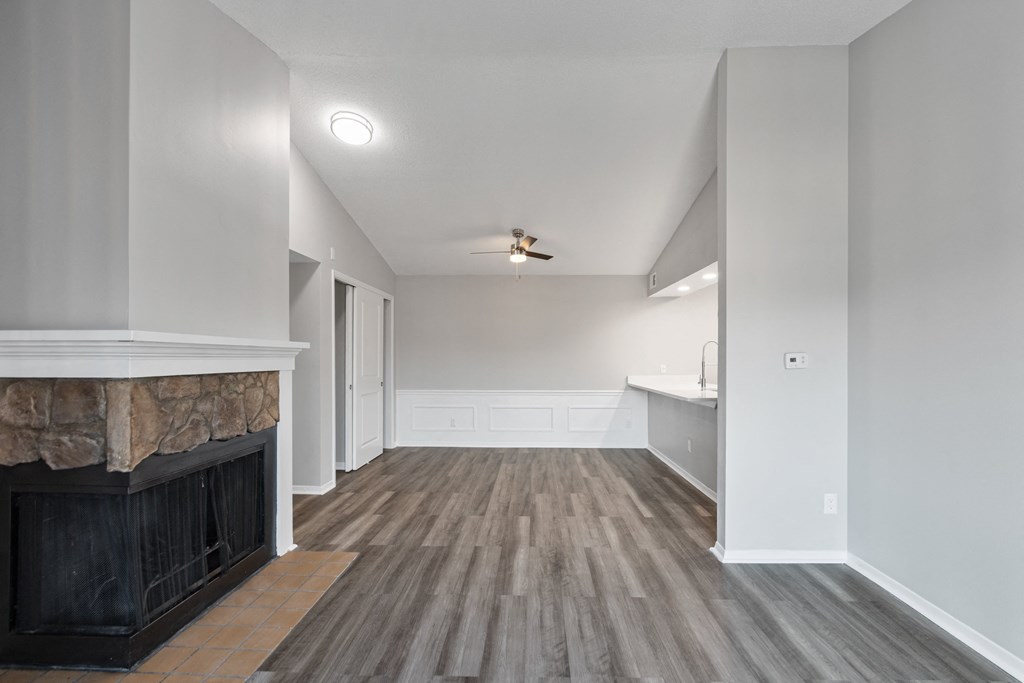 an empty living room with a fireplace and a kitchen