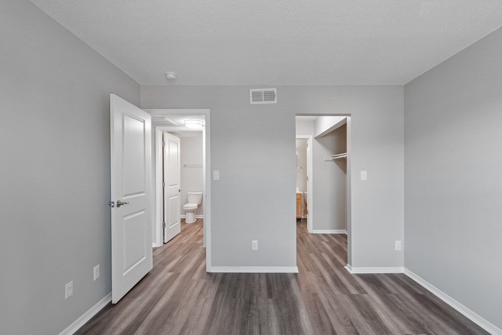 the living room of an apartment with white walls and wood flooring