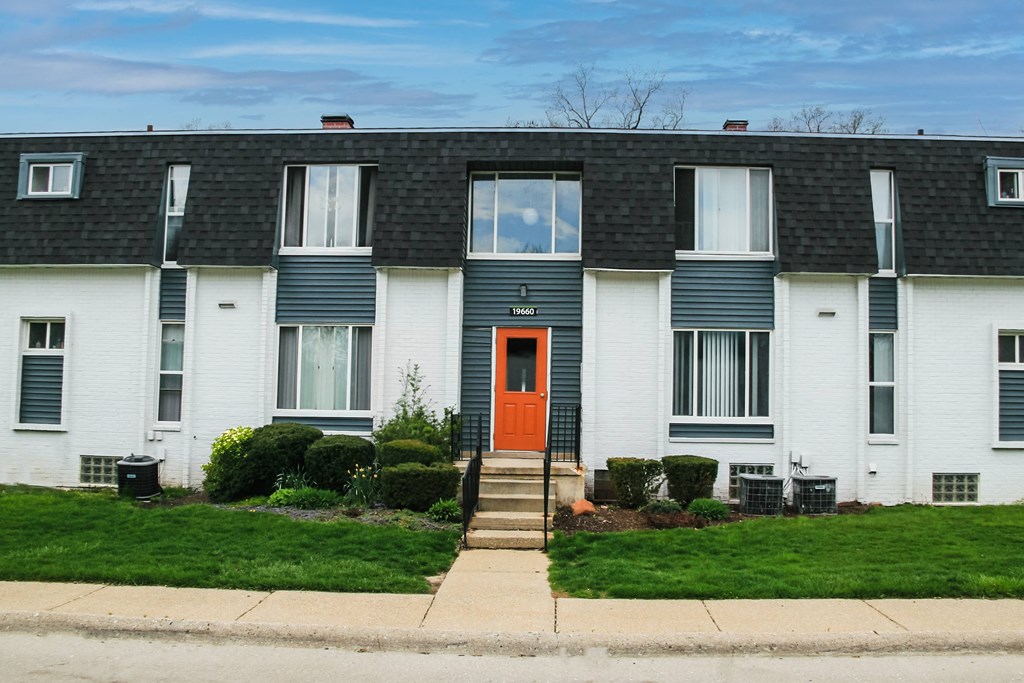 the front of a white house with a red door