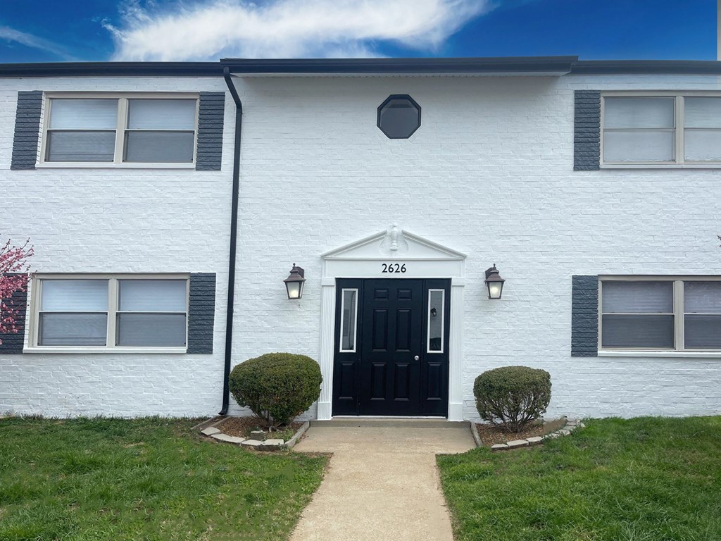 the front of a white house with a black door
