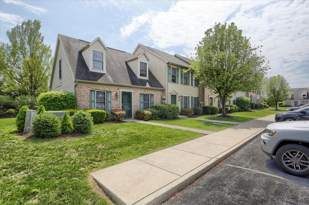 A house with a green lawn and a tree in front.