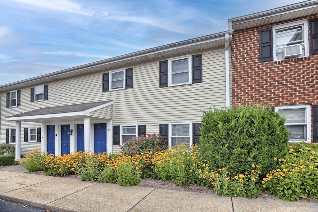 a white house with blue doors and a garden in front of it