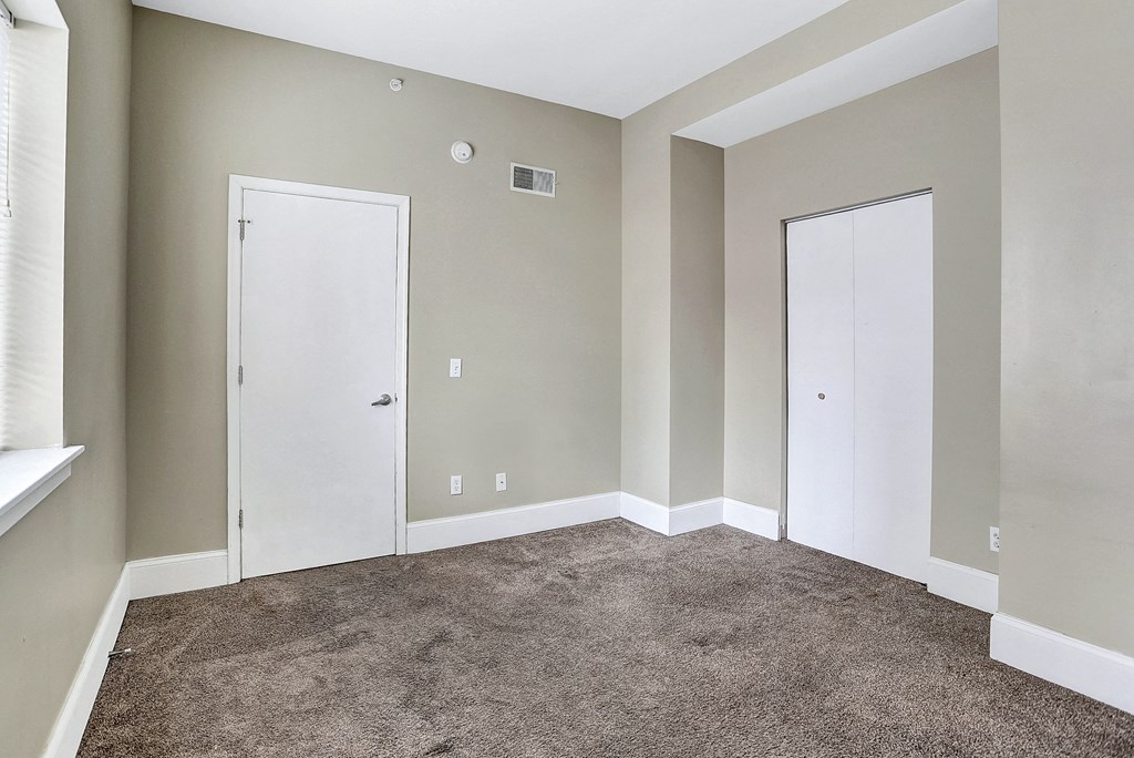 an empty room with carpet and two doors