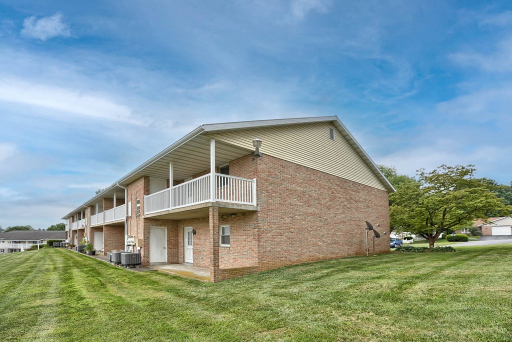 the outlook of a brick apartment building with a balcony and grass