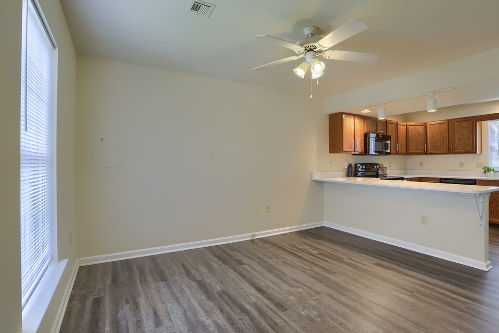 A room with a ceiling fan and a counter with a microwave.