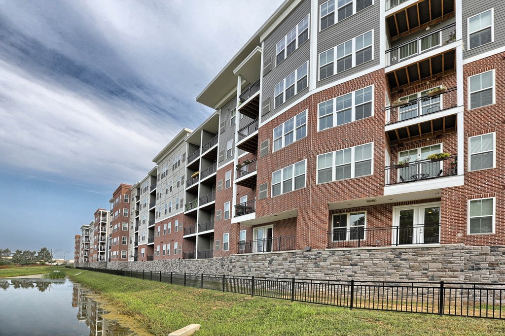 an exterior view of an apartment building next to a body of water