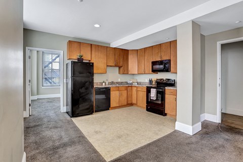 an empty kitchen with wooden cabinets and a black refrigerator