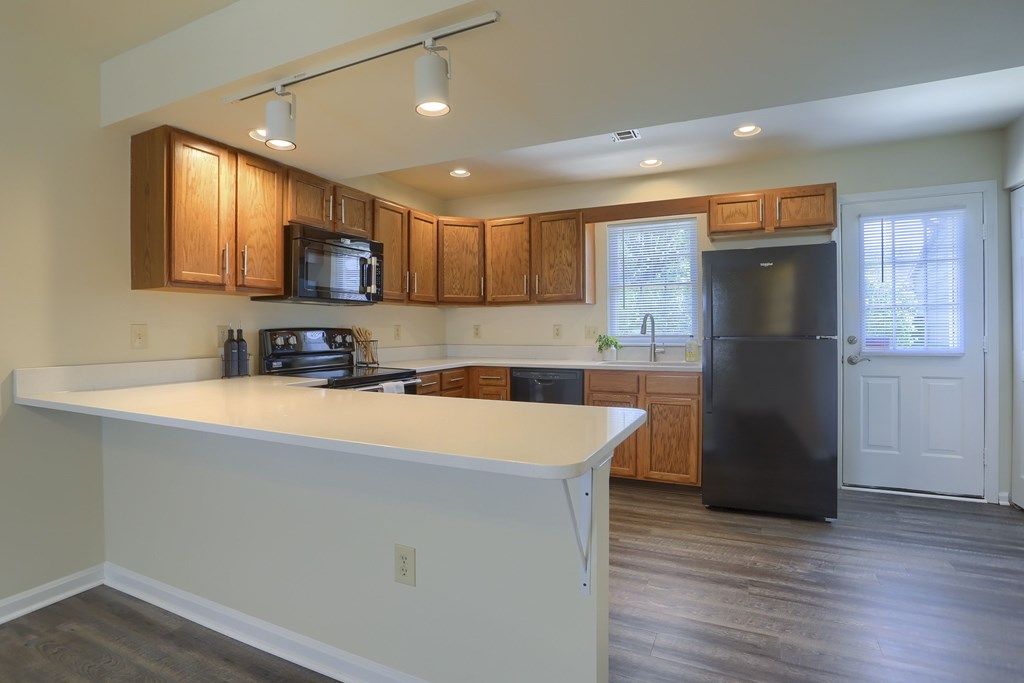 A kitchen with a black refrigerator and wooden cabinets.