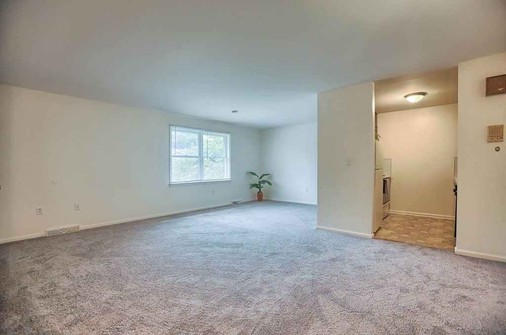 an empty living room with white walls and a window