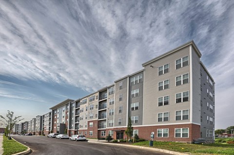 a large apartment building on a street with a cloudy sky