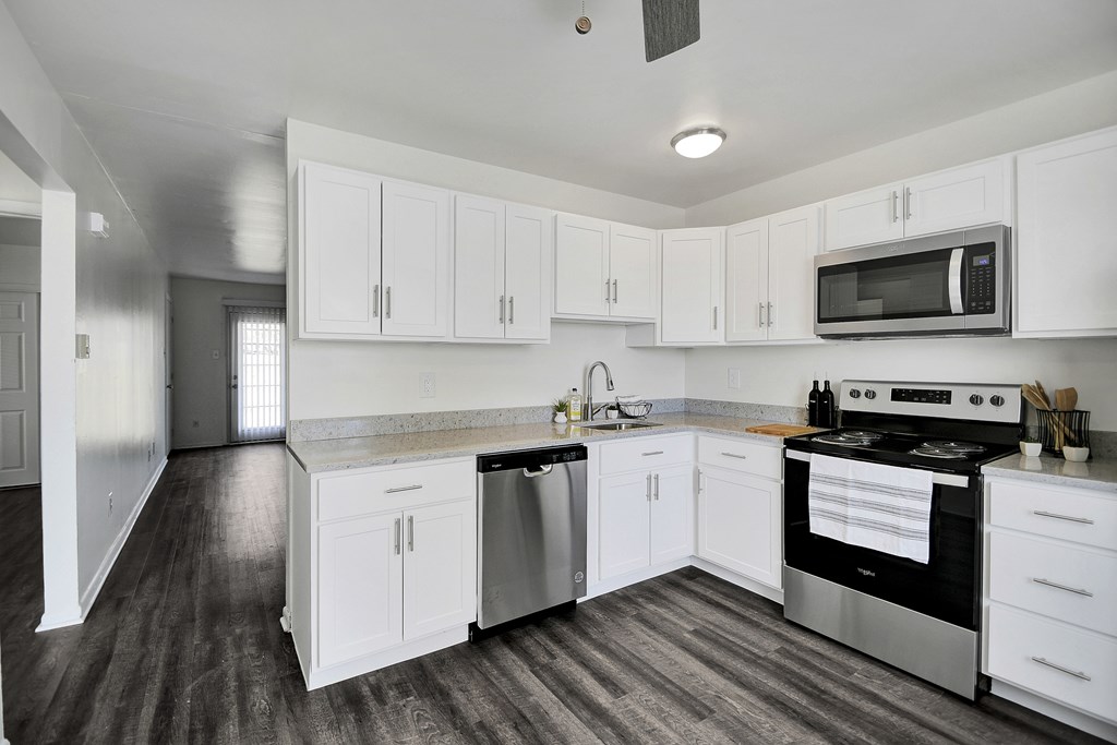 A kitchen with white cabinets and a stainless steel dishwasher and oven.