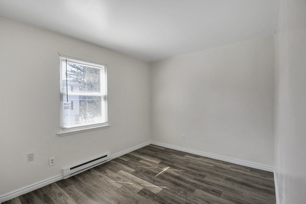 A room with a window and wooden flooring.