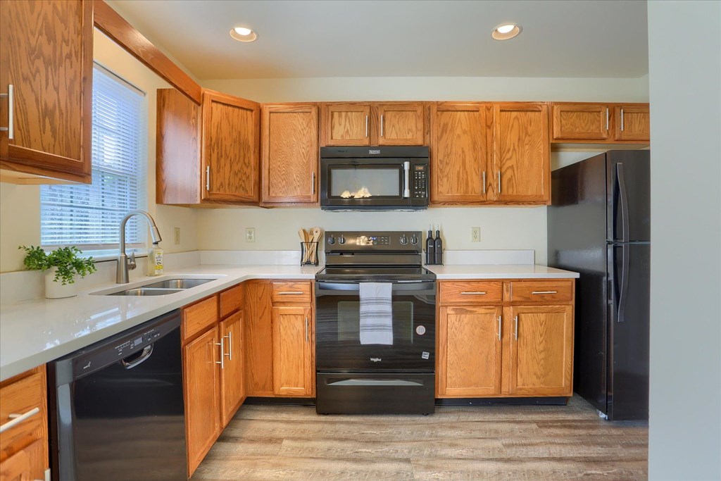 A kitchen with wooden cabinets and black appliances.