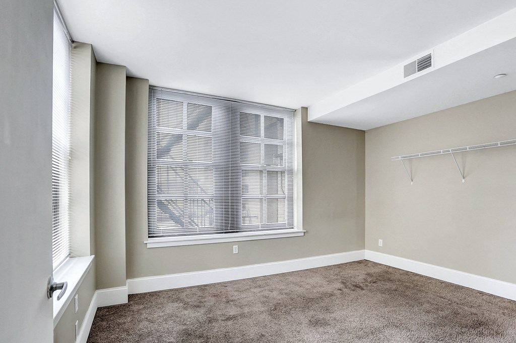an empty room with a large window and a carpeted floor