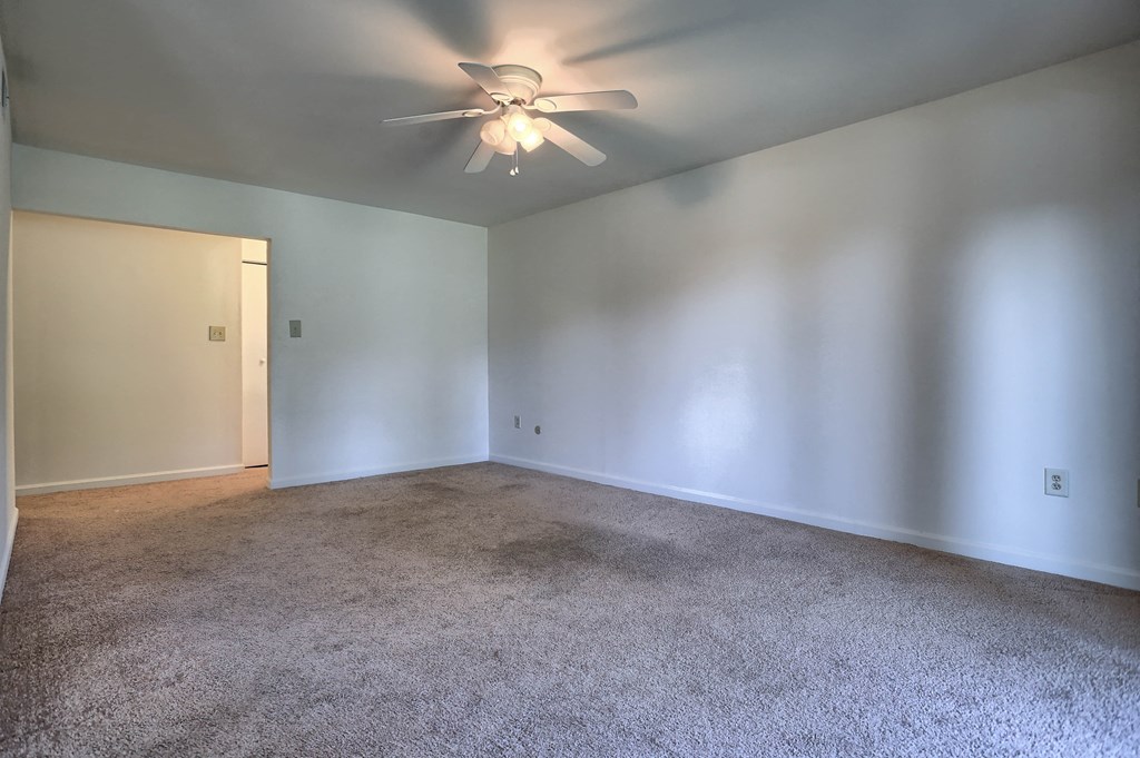 an empty living room with white walls and a ceiling fan