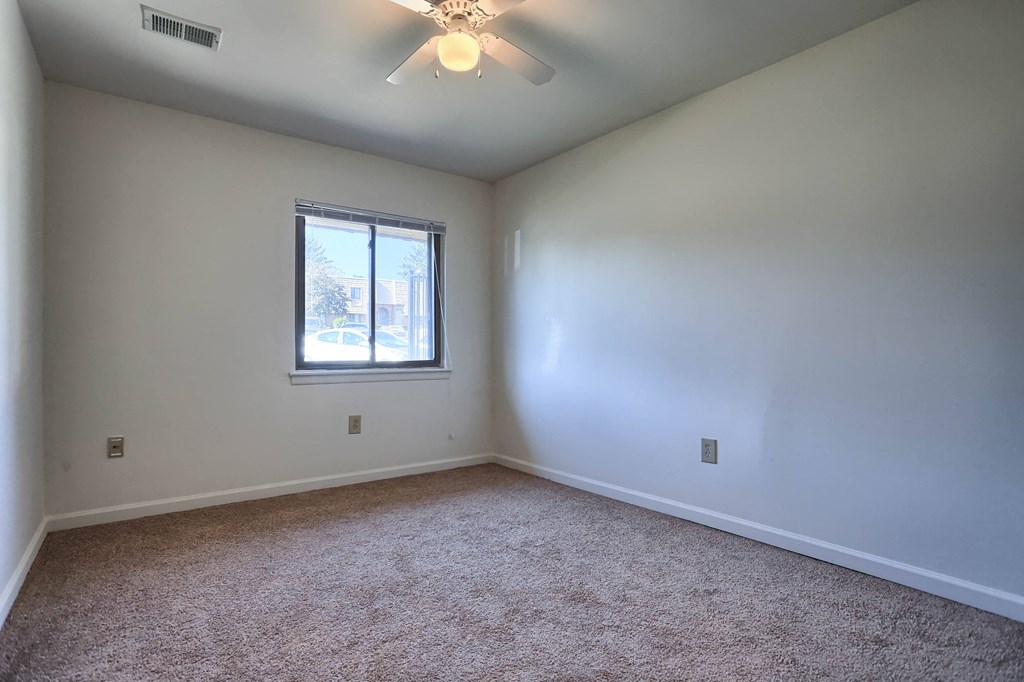 A room with a ceiling fan and a window.