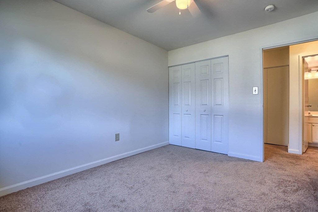 A room with a carpeted floor and a ceiling fan.