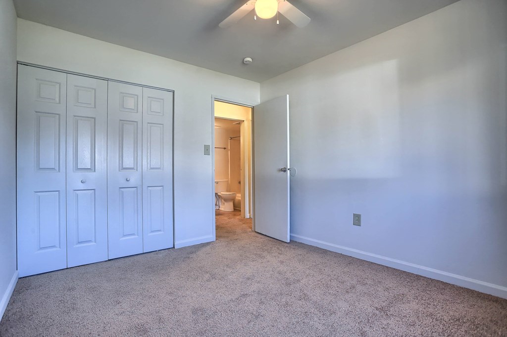 A room with white doors and carpeted floor.