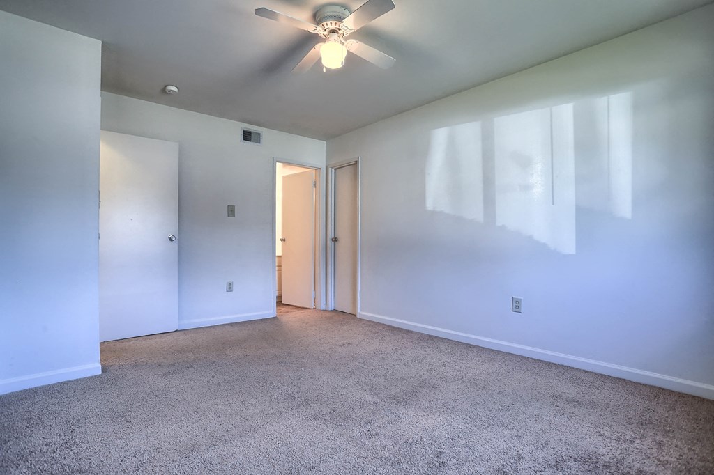 an empty living room with white walls and a ceiling fan