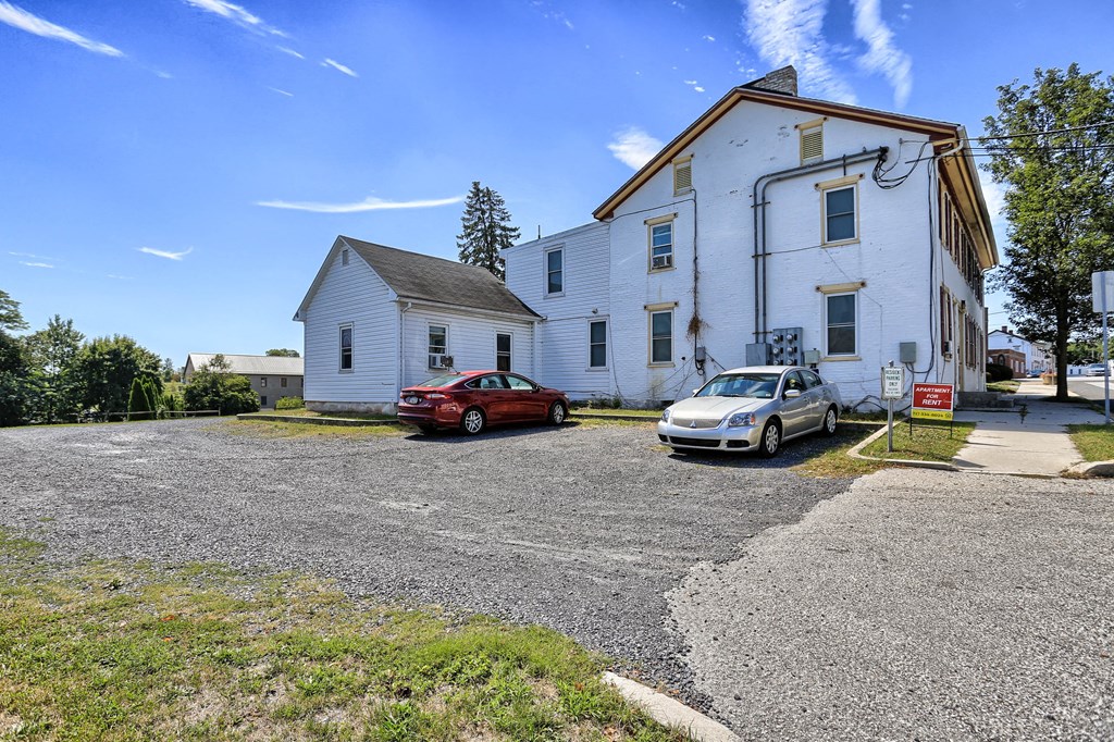 an old white building with two cars parked in front of it