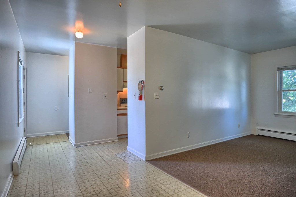 a empty living room with white walls and a tile floor