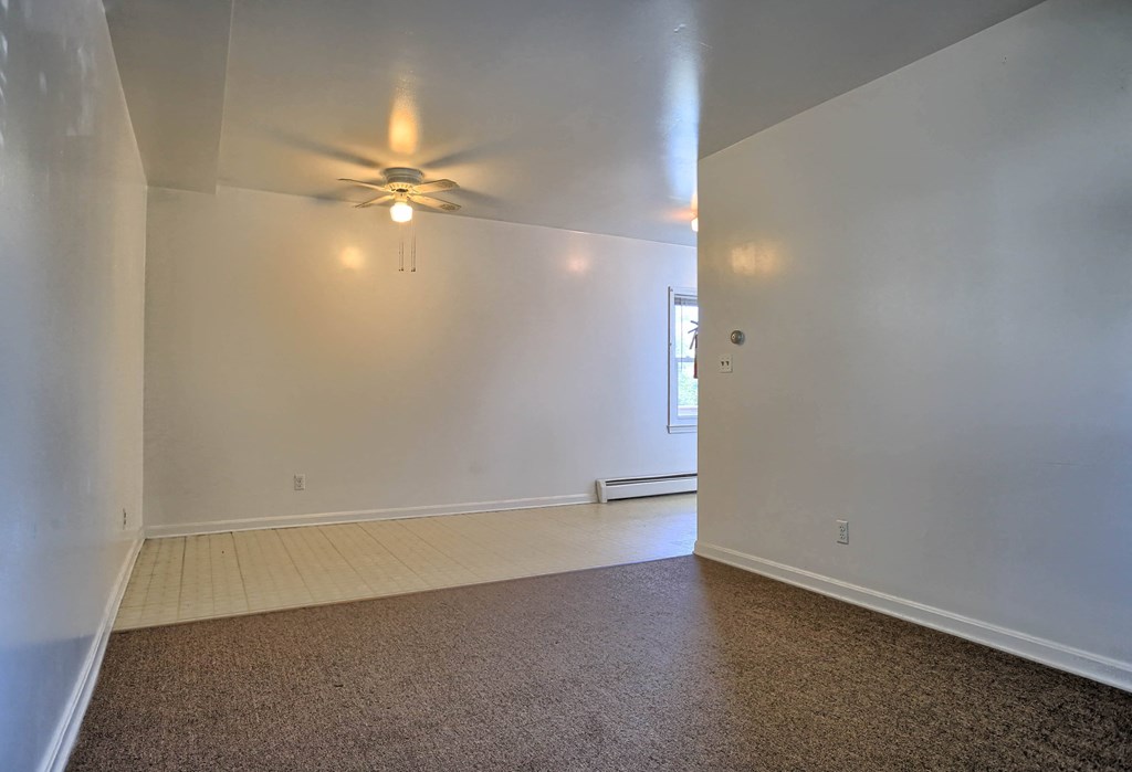 a living room with white walls and a ceiling fan