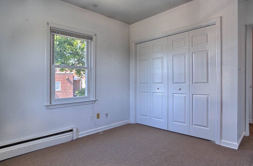 a bedroom with white walls and a window and two closets