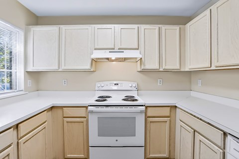 A kitchen with a white stove and wooden cabinets.