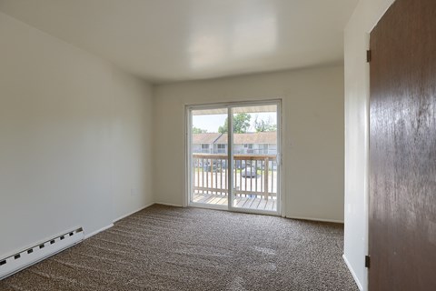 an empty living room with a door to a balcony
