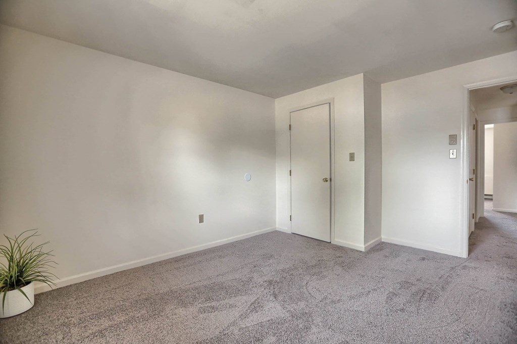 an empty living room with white walls and carpet