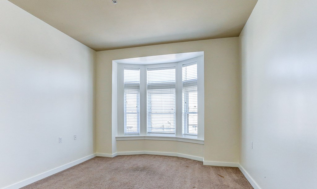 an empty room with a large window and white walls