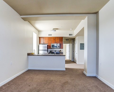 an empty living room and kitchen with a counter top and a refrigerator