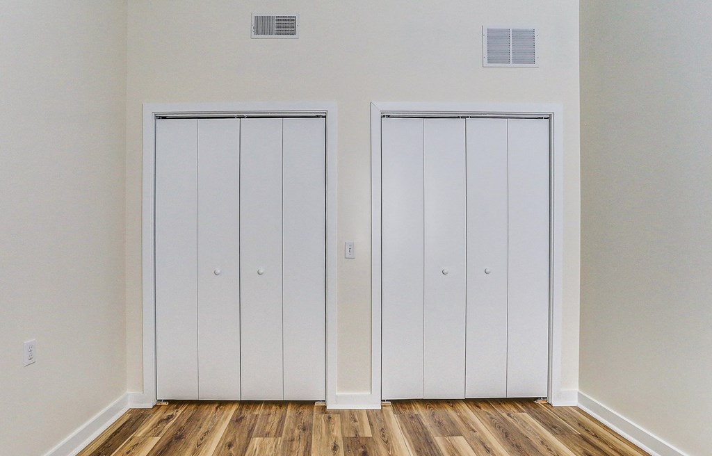 an empty room with two closets and wooden floors