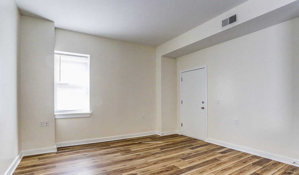 a bedroom with white walls and wood flooring and a door