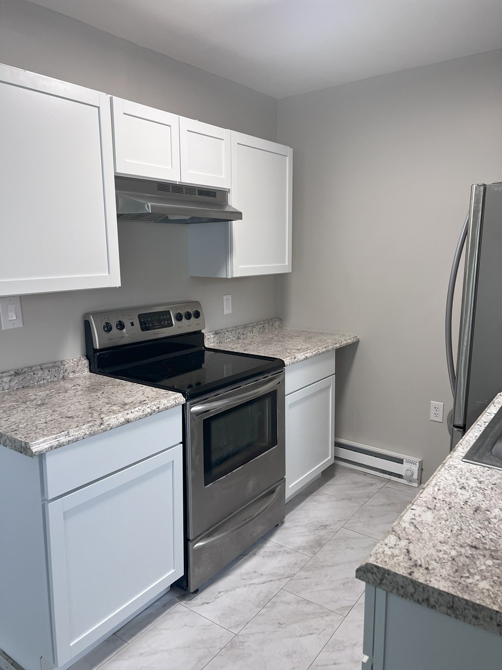 A kitchen with white cabinets and granite countertops.