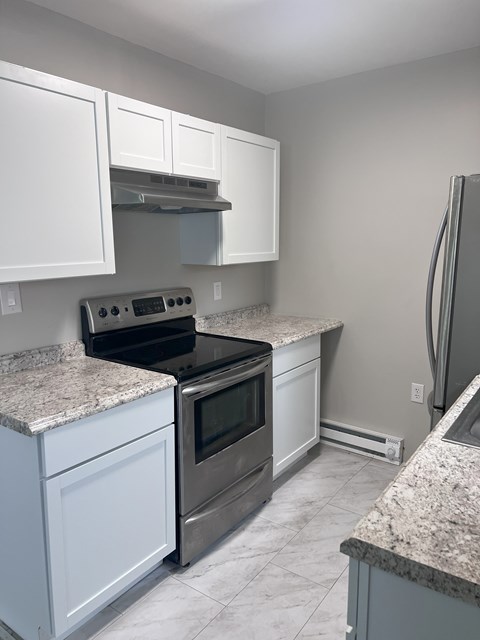 A kitchen with white cabinets and granite countertops.