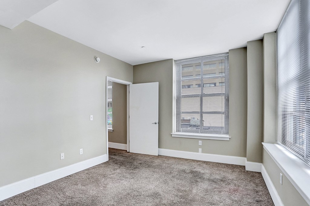 an empty living room with a large window and a door to a closet