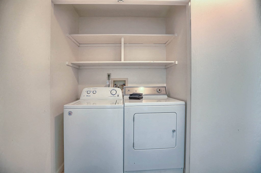 a small laundry room with a washer and dryer and a shelf above it
