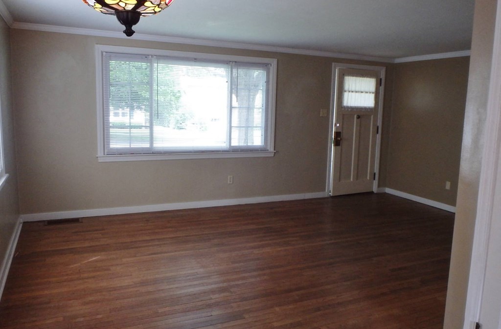 an empty living room with wooden floors and a window