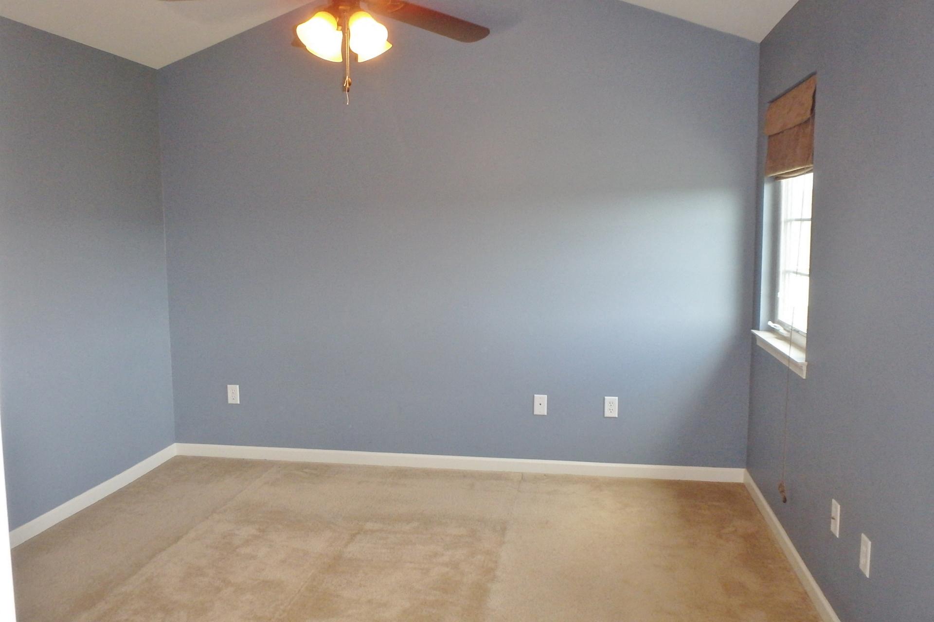 an empty room with blue walls and a ceiling fan