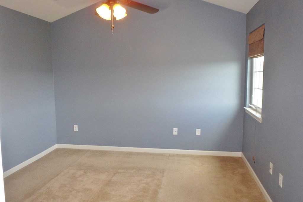 an empty room with blue walls and a ceiling fan