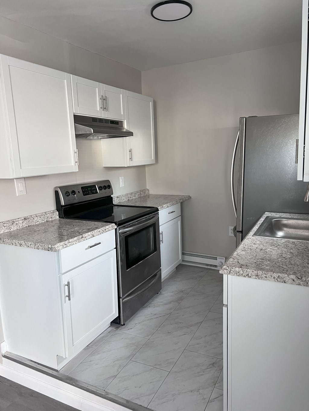 A kitchen with white cabinets and a granite countertop.