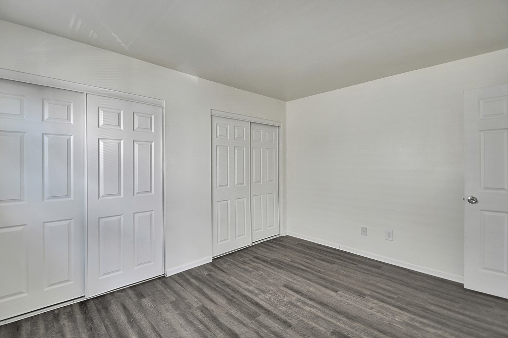 A room with white doors and grey flooring.