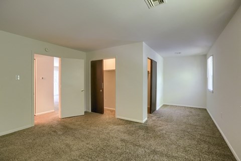 A spacious room with carpeted floor and white walls.