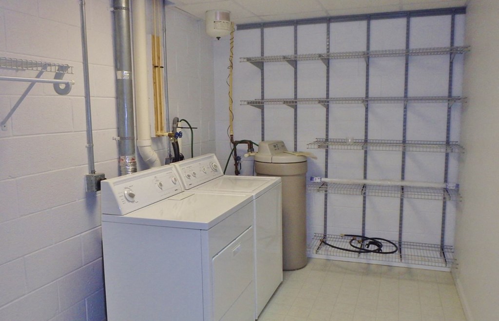a laundry room with a washing machine and a trash can