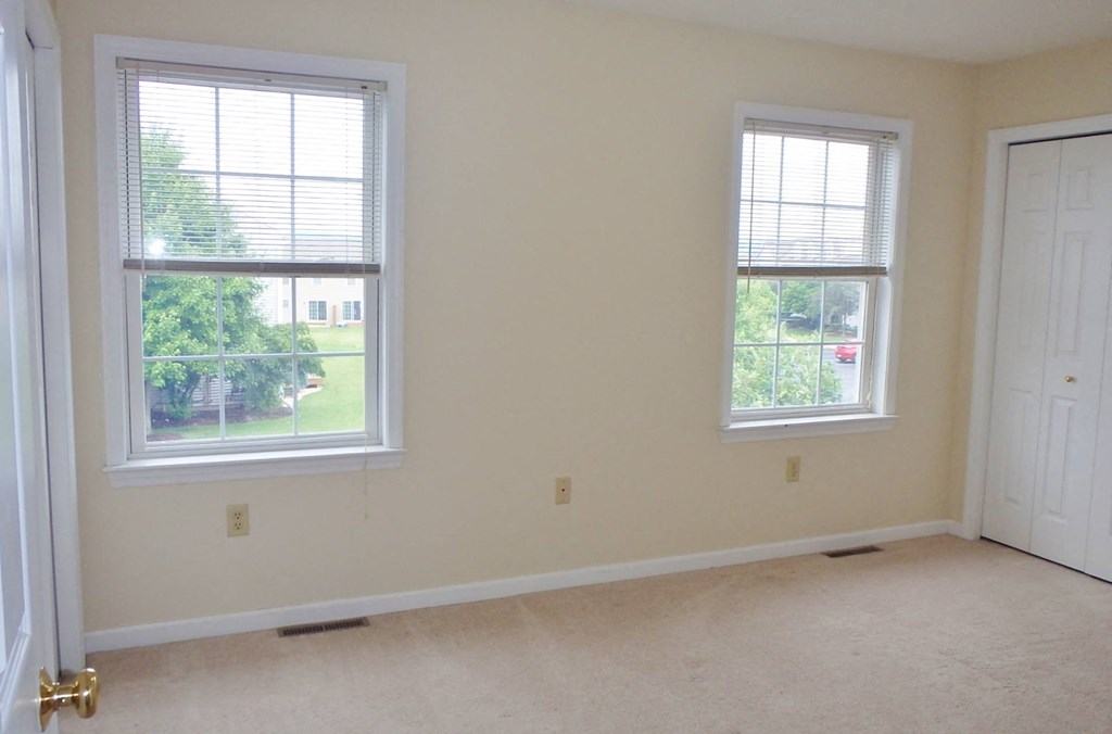 an empty room with two windows and a door