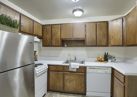 A kitchen with wooden cabinets and a stainless steel refrigerator.